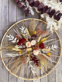 an arrangement of dried flowers in a wicker basket on a wooden floor next to feathers