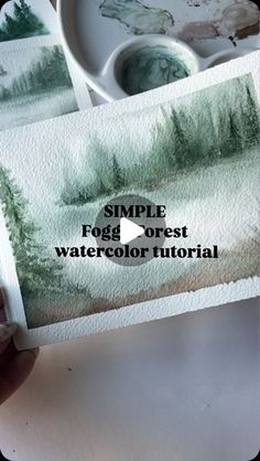 someone is holding up some watercolor paper with the words simple fog forest on it