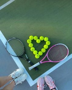 tennis rackets and balls are arranged on the court with a heart shaped wreath made out of them