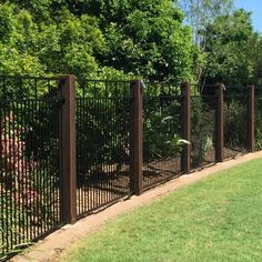 a fenced in area with green grass and trees