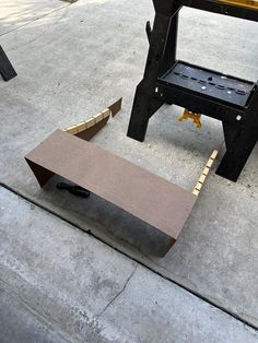 a bench sitting on top of a cement ground next to a piece of equipment that is attached to it