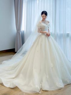 a woman in a white wedding dress standing next to a window wearing a long veil