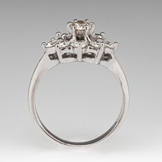 an engagement ring with three stones in the center and two diamonds at the bottom, on a gray background