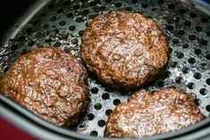 three hamburger patties cooking in an air fryer