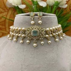 a necklace and earring set with pearls on a mannequin neckline, surrounded by flowers