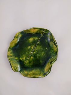 a green leaf shaped plate sitting on top of a table