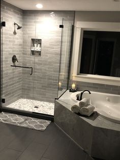 a bathroom with a walk in shower next to a sink and bathtub, surrounded by gray tile