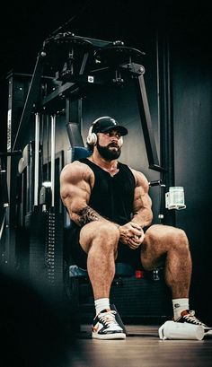 a man sitting on top of a chair in front of a gym equipment machine with his legs crossed