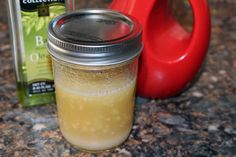 a glass jar filled with liquid sitting on top of a counter next to a bottle