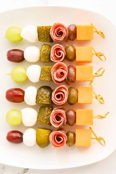 appetizers are arranged on skewers with cheese, grapes and pickles