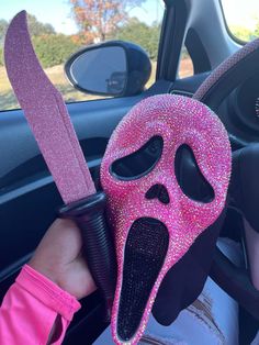 a pink mask with a knife sticking out of it's mouth in a car