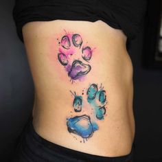 a woman's stomach with an animal paw tattoo on the side, and watercolor paint splatters all over it