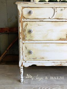 an old white dresser with flowers on top