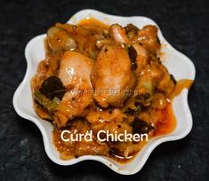 a white bowl filled with meat and vegetables on top of a black tablecloth covered floor