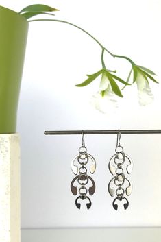 Edgy glamor, botanical style: these statement chandelier earrings were inspired by trailing clusters of flowers, reinterpreted in polished, modern industrial style. The perfect conversation piece for a conference or a concert. Stainless steel hardware linked with titanium, with hypoallergenic titanium ear wires; 2.75 inches long. Shown modeled with the Laburnum Pendant. From the Mechanical Garden collection. Sign up for free US shipping on your first order! Free US shipping on all orders of $150 Black Tie Outfits, Statement Chandelier, Neutral Earrings, Hardware Jewelry, Statement Chandeliers, Industrial Jewelry, Easy Day, Garden Jewelry, Upcycled Jewelry