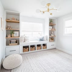 a white room with lots of shelves and baskets on top of the shelf, along with a large rug