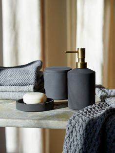 two soap dispensers on a table next to towels