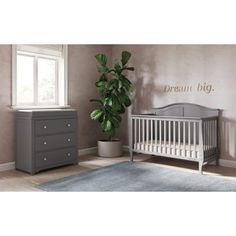 a baby's room with a crib, dresser and potted plant