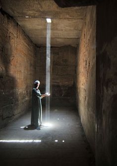 a person standing in an empty room with light coming from the ceiling