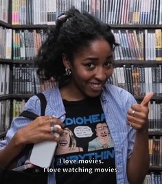 a woman is standing in front of a bookshelf and pointing at the camera