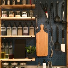 an organized kitchen with lots of spices and cooking utensils hanging on the wall