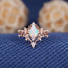 an opal and diamond ring sits on a blue cloth