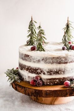 a cake with frosting and pine trees on top sitting on a wooden platter