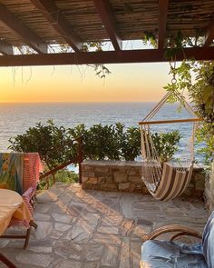 a hammock hanging from the side of a stone building next to an ocean