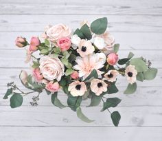 a bouquet of flowers sitting on top of a white wooden table next to a wall