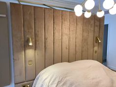 a bedroom with wood paneling on the wall and lights hanging from it's ceiling