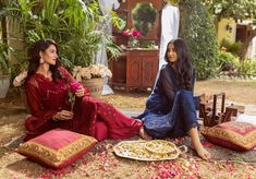 two women sitting on the ground in front of flowers