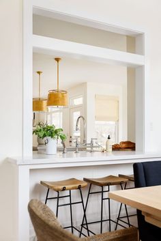 an open kitchen and dining room with stools in front of the countertop area