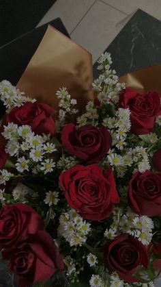 a vase filled with red roses and daisies on top of a marble countertop