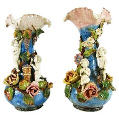 two blue vases with flowers and statues on them