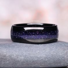 The Starry Night Men's Wedding Band is a captivating piece crafted from durable tungsten carbide, designed to symbolize the eternal bond of marriage. Measuring 8mm in width, this unique ring features an enchanting inlay of crushed galaxy sandstone, evoking the mesmerizing beauty of a starlit sky. The intricate interplay of dark and shimmering particles within the band captures the essence of outer space, making it a perfect choice for those who are inspired by the cosmos. This wedding band blend Sandstone Ring, Space Ring, Starlit Sky, Space Rings, Couples Ring, Mens Wedding Bands Tungsten, The Starry Night, Mesmerizing Beauty, Tungsten Wedding Bands