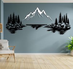 a living room with a chair and wall decal in the shape of mountains, lake and pine trees