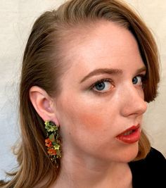 Gorgeous chandelier earrings in hues of amber, citrus, dusty green and a pop of orange makes this pair of earrings stand out. Hand beaded with hand painted resin flowers. This is a quality piece of jewelry that will last a life time. Created by designer Colleen Toland who has been creating her unique style of vintage jewelry for more than 30 years. Earrings measure .5 inches by 1 inch. All metal components are nickel free and are plated in antique gold. All our post earrings are hypoallergenic. Bohemian Green Flower Earrings For Party, Orange Flower Shaped Earrings For Party, Orange Flower Earrings For Party, Earrings Stand, Painted Resin, Dusty Green, Earring Stand, Purple Earrings, Resin Flowers