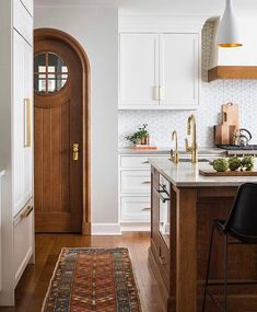 a kitchen with white cabinets and wooden flooring next to a counter top on an area rug