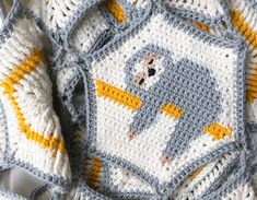 an elephant crocheted blanket on top of a white tablecloth with yellow and gray trim