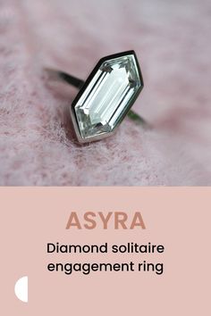 a diamond soltation ring sitting on top of a pink blanket with the words asyra above it