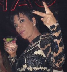 a woman is holding up her peace sign and drinking