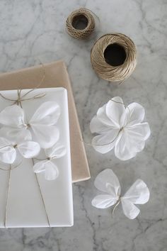 white paper flowers and twine on a marble table with some crafting supplies next to it