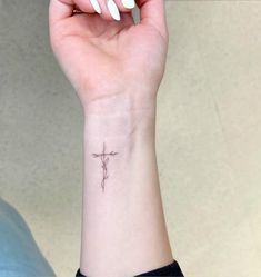 a woman's wrist with a small cross tattoo on the left side of her arm