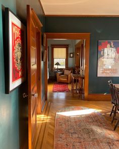 an open door leading to a dining room with blue walls and wood floors, along with a rug on the floor