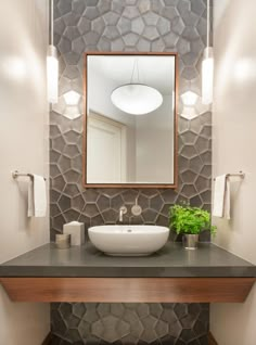 a bathroom with a sink, mirror and lights on the wall above it's counter