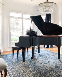 a grand piano in a living room with chandelier and rug on the floor