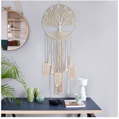 a table with a mirror and some plants on top of it next to a wall hanging