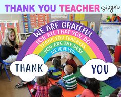 a group of children sitting on the floor in front of a thank you teacher sign