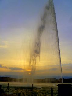 a water spewing out from the ground at sunset