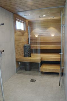 a bathroom with a wooden bench and tiled floor next to a shower stall that has glass doors on both sides